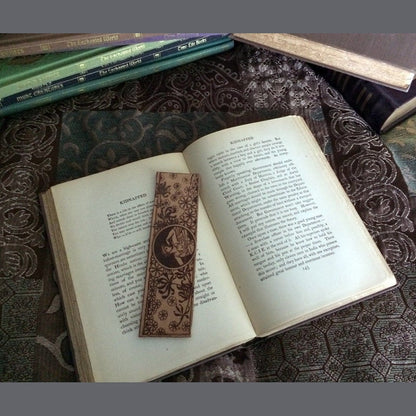 The bookmark of a Roman or Greek woman and wild flowers resting on an open antique book.