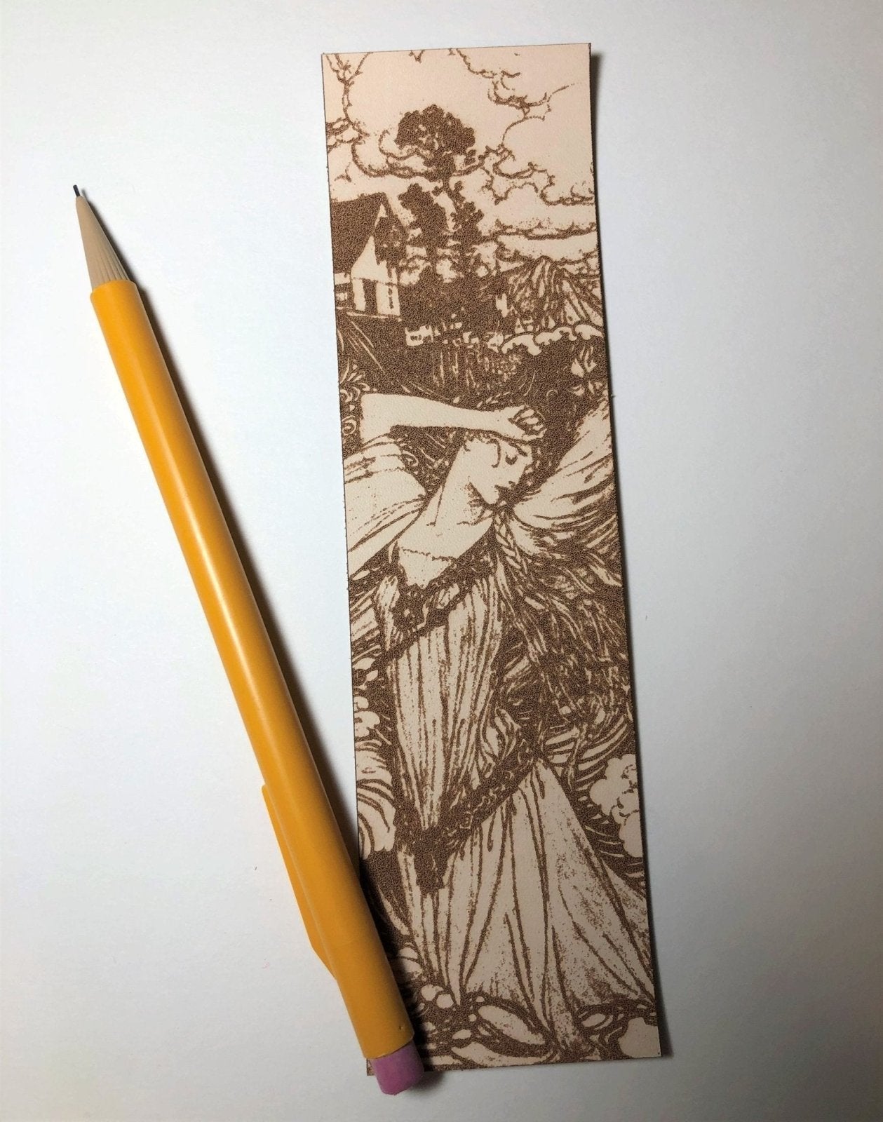 The woman in the water bookmark next to a pencil for scale. Woman in the Water Leather Bookmark Bookmarks Raven King Crafts