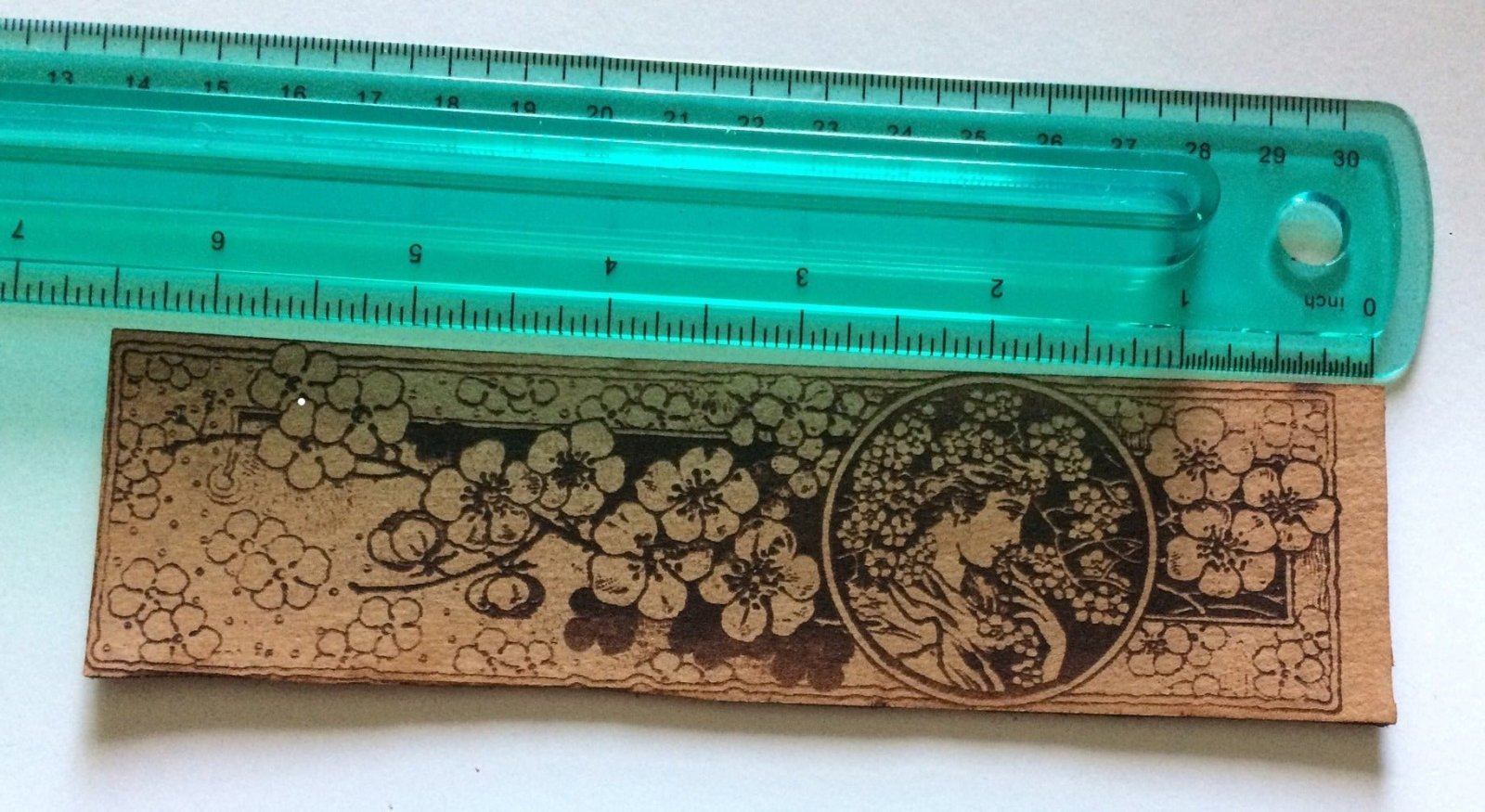 A bookmark with the art of a beautiful woman next to a ruler for scale