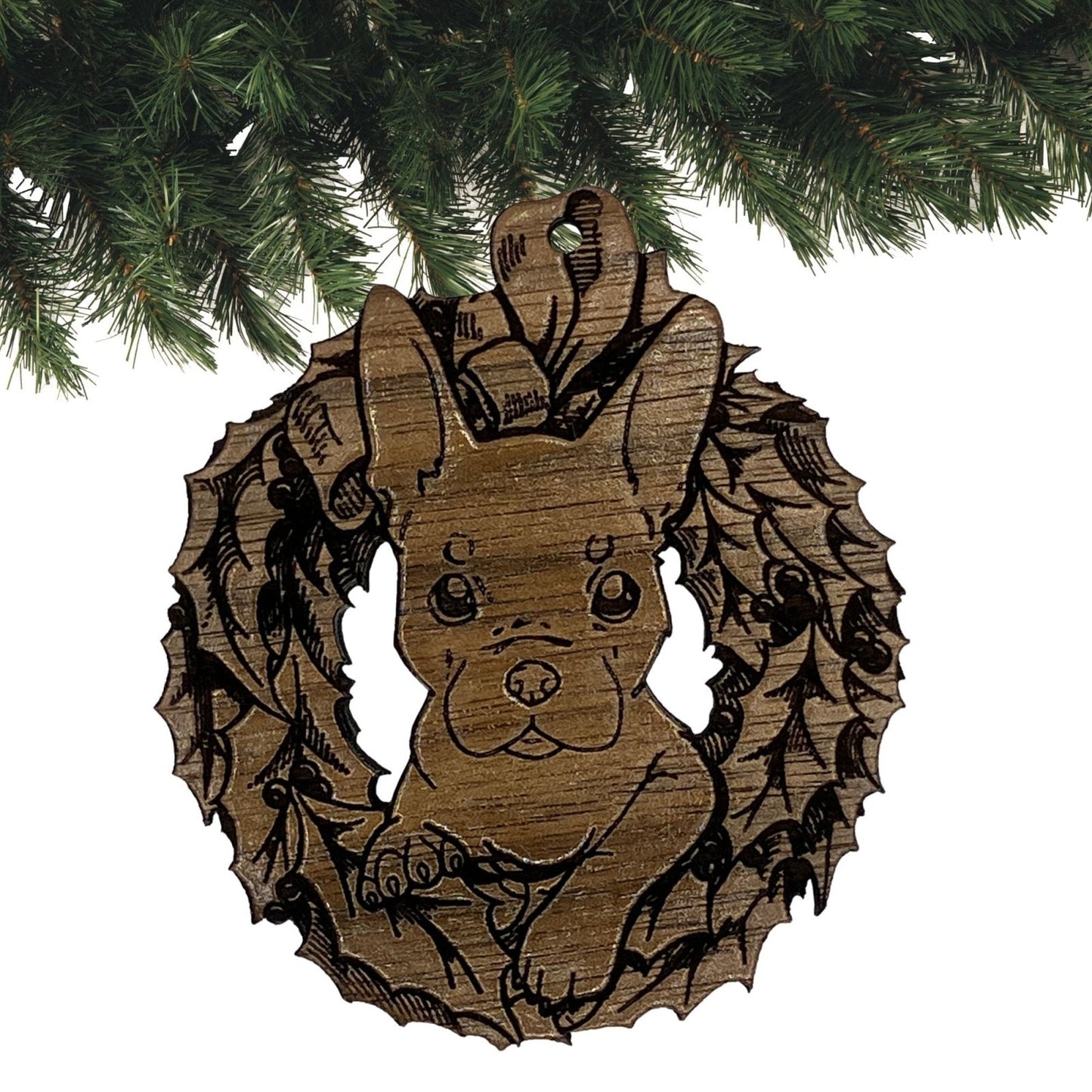 A photograph of the dark wood French Bulldog ornament. The ornament itself is cut in the shape of a wreath with the puppy's head popping through the middle.