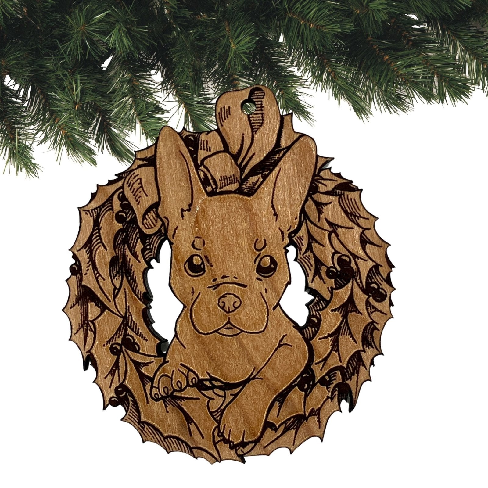 The reddish variety of the French Bulldog ornament. This wooden ornament shows a puppy's head sticking out of a Christmas wreath engraved on it. The ornament is then sanded and given a clear glossy coat to protect the wood.