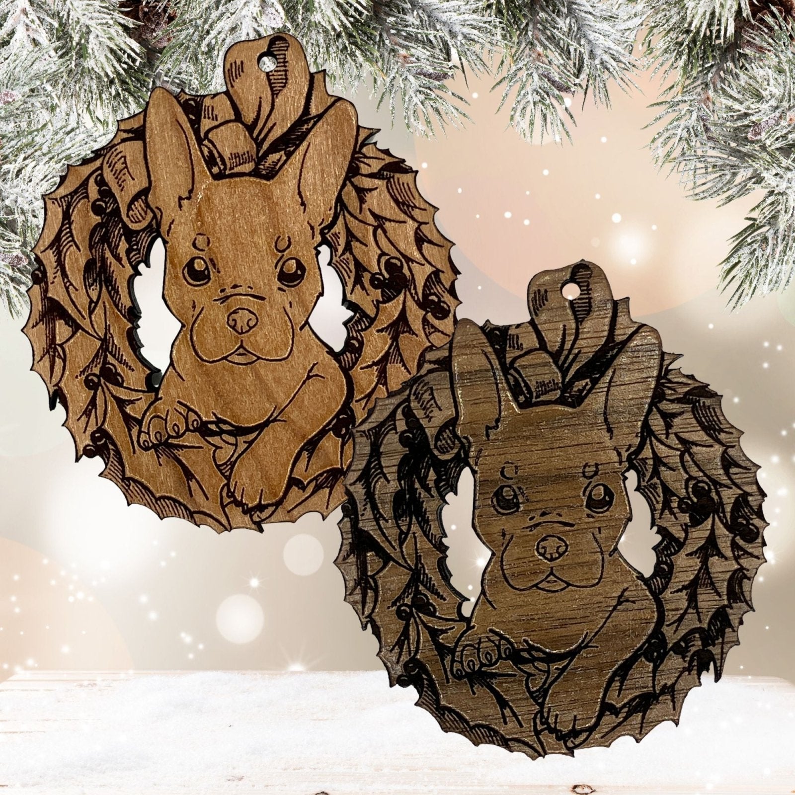 2 of the French Bulldog ornaments side by side. The top left one is the reddish color wood and the bottom right one is the dark color. Each ornament shows the French Bulldog puppy's head popping through the Christmas wreath. Wood French Bulldog Ornaments Ornament Raven King Crafts
