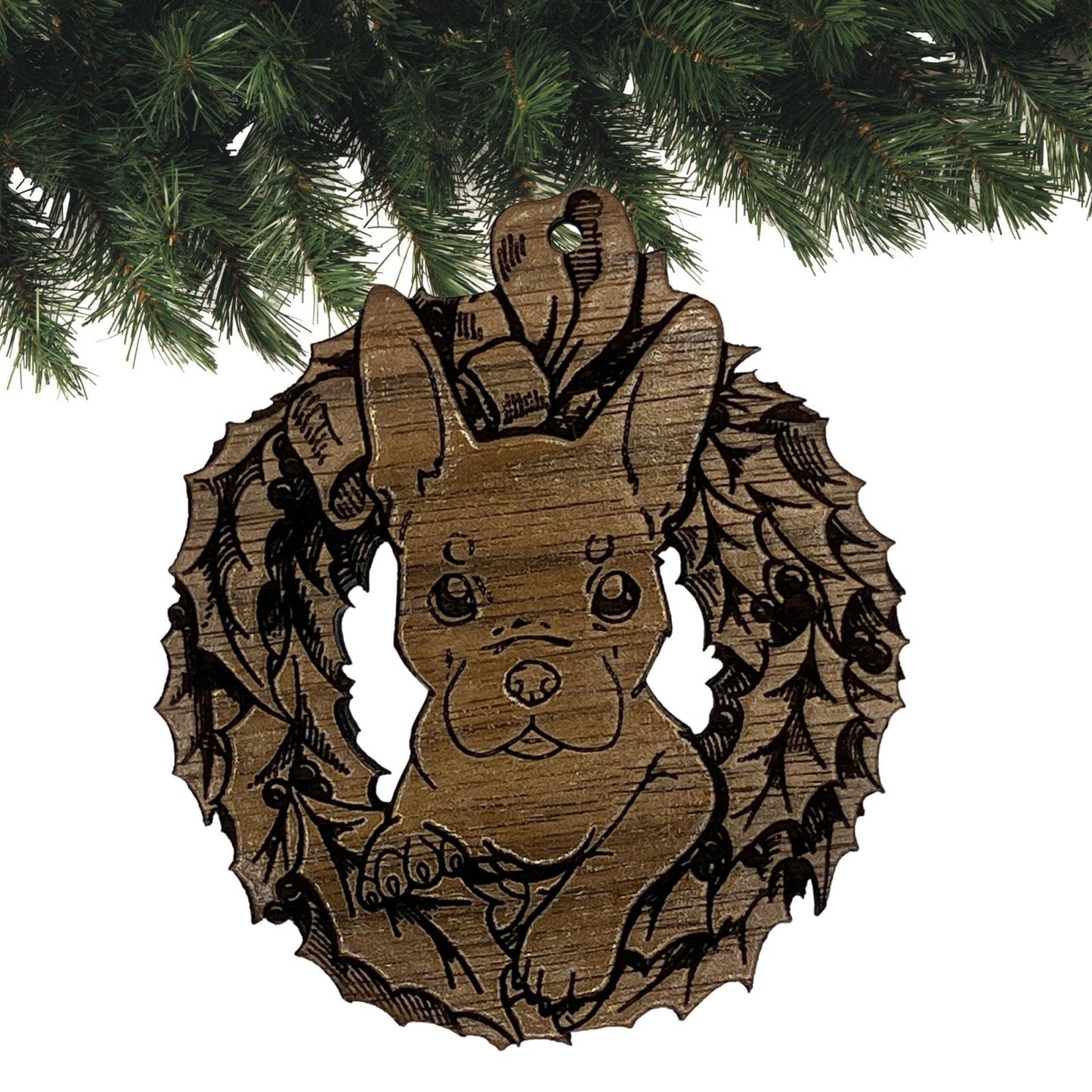 A photograph of the dark wood French Bulldog ornament. The ornament itself is cut in the shape of a wreath with the puppy's head popping through the middle. Wood French Bulldog Ornaments Ornament Raven King Crafts