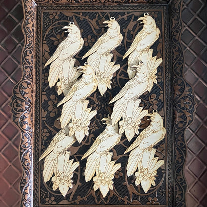 A photograph of 8 wooden raven shaped ornaments resting on a metal tray.