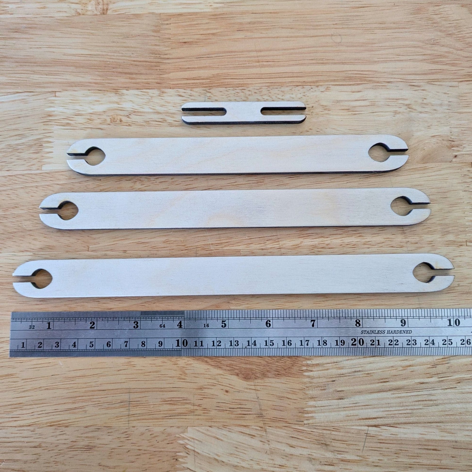The 4 shuttle sticks next to a metal ruler for scale. Wooden Shuttle Stick Set - 4 Weaving Shuttles Art & Crafting Materials Raven King Crafts